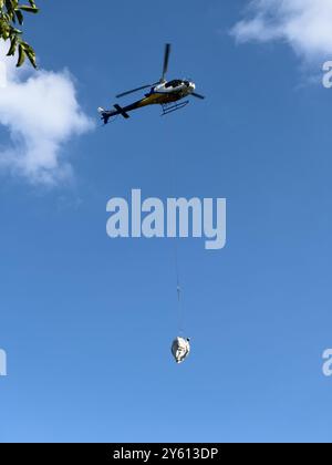 Ein Hubschrauber, der ein Paket in den Bergen des Comer Sees transportiert Stockfoto