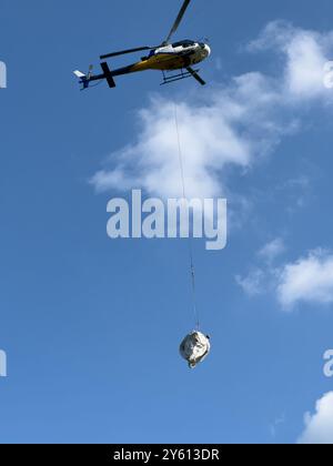 Ein Hubschrauber, der ein Paket in den Bergen des Comer Sees transportiert Stockfoto