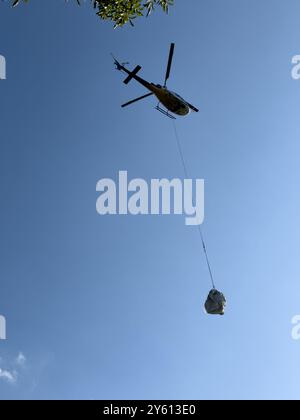 Ein Hubschrauber, der ein Paket in den Bergen des Comer Sees transportiert Stockfoto