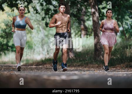 Gruppe von jungen Erwachsenen, die an einem sonnigen Tag gemeinsam im Park joggen und Fitness und aktiven Lebensstil fördern Stockfoto