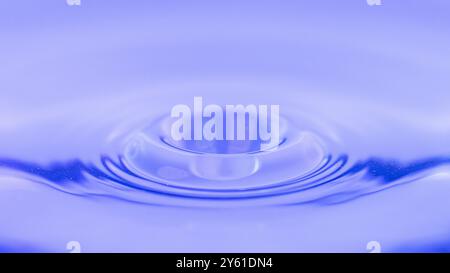 Minimalistische Fotografie, von einem Wassertropfen, einem Spritzer, einer Welle, die sich auf der Wasseroberfläche ausbreitet, Bild, das Ruhe, Meditation, Ruhe anregt Stockfoto