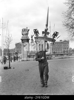 London, Bruce Duthie, der aus Dundee, Schottland kommt, wird eine dekorative goldfarbene Krone aufsetzen - eine von vielen, die im Einkaufszentrum für Prinzessin Margarets Hochzeit nächsten Monat errichtet wird. Im Hintergrund befindet sich der Buckingham Palace. 27. April 1960 Stockfoto