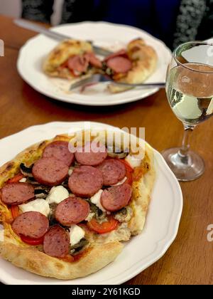 Pizza auf einem Teller mit einem Glas Weißwein Stockfoto