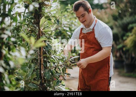 Junger Gärtner mit Down-Syndrom, der Pflanzen im Garten pflegt Stockfoto