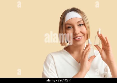 Schöne reife Frau mit Flaschen ätherischen Öls vor farbigem Hintergrund Stockfoto