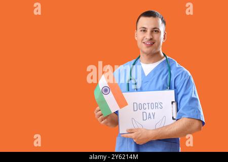 Männliche Krankenschwester mit Klemmbrett mit Text DOCTOR's DAY und Flagge von Indien auf orangem Hintergrund Stockfoto