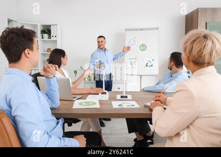 Männlicher Ingenieur mit Recyclingschildern, die seinen Kollegen im Büro eine Präsentation geben Stockfoto