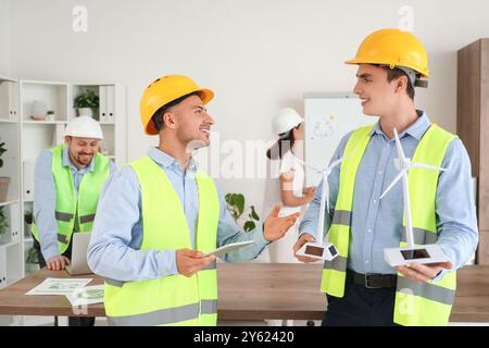 Männliche Ingenieure mit Windturbinenmodellen und Tablet-Computer im Büro Stockfoto