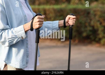 Schöne reife Frau trainiert mit Wanderstöcken im Park, Nahaufnahme Stockfoto