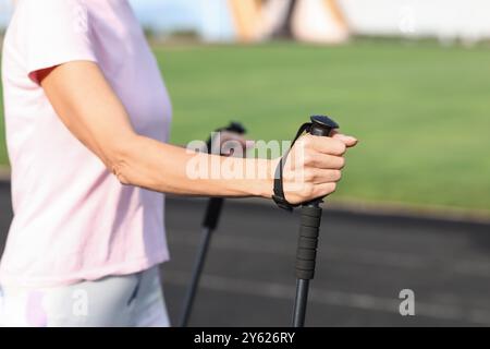 Schöne reife Frau, die mit Gehstöcken im Stadion trainiert, Nahaufnahme Stockfoto