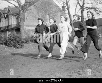 Mitcham, das für die bevorstehenden Olympischen Spiele ausgebildet wird, ist auf dem News of the World Sports Ground beschäftigt und sind Mädchen aus allen Bereichen des Lebens, von Bankbeamten bis zu Hausfrauen. Sie stehen unter dem wachsamen Auge von Mrs. M. Cornell, Trägerin der britischen Langsprungrekord und offizieller Olympiasieger. Das Bild zeigt: Von links nach rechts - Frau E. Brenner (Hausfrau und Langspringer), Frau D.V.Schenk (Bankangestellte und Langspringer), Frau K. Dyer (Champion Shot-Putter, Süßwarenarbeiterin), Miss L. Cornell (die noch in der Schule ist) und Frau M. Cornell, der Trainer in Mitcham. 25. Januar 1948 Stockfoto