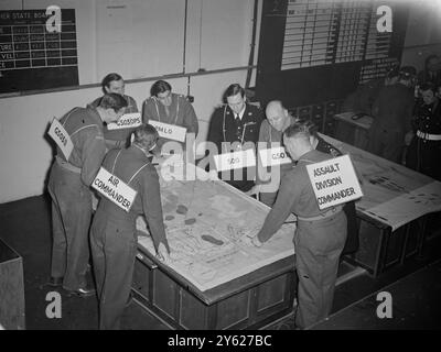 Combined Operations, die eine entscheidende Rolle bei allen letzten siegreichen Feldzügen des jüngsten Krieges spielte und gelernt wurde, Mitglieder aller Zweige der Dienste an der Combined Operation School in Remington, North Devon, zu präsentieren. Männer der Marine, der Armee, der Marine und der Luftwaffe, alle unter Anleitung in allen Auswirkungen des amphibischen Angriffs. Das Bild zeigt: Identifikationsschilder werden von Beamten im „H.Q.Ship“ in Fremlingham getragen, während sie eine Karte des „Einsatzgebiets“ studieren. Die Vorstände geben den Männern, die den Kurs durchlaufen, eine klare Vorstellung von den Verantwortlichkeiten jedes Teils des einheitlichen Kommandos. Stockfoto