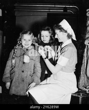 35 ausgestellte Kinder aus Deutschland kamen an der Liverpool Street Station an, um einen 4- bis 6-jährigen Aufenthalt in diesem Land zu beginnen, unter der Schirmherrschaft des National Children's Home and Waisenhaus of Highbury Park, London. Die Kinder sind die ersten einer hundertköpfigen Gruppe, die ins Waisenhaus in Alverstoke, Hants, gehen wird, um ein neues Leben in Großbritannien zu beginnen. Sie werden schließlich nach Deutschland zurückkehren, um beim Wiederaufbau der kriegszerstörten Jugend des Landes zu helfen. Das Bild zeigt: Die kleine Nada wird von der jungen Betrügerin Hildar begierig beobachtet und lässt sich von der deutschen Krankenschwester, die die Kinder begleitete, ihre Langhaar flechten Stockfoto