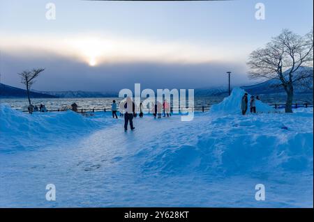 Touristen am gefrorenen Ufer und Schnee des Shikotsu-Sees in Hokkaido, Nordjapan Stockfoto