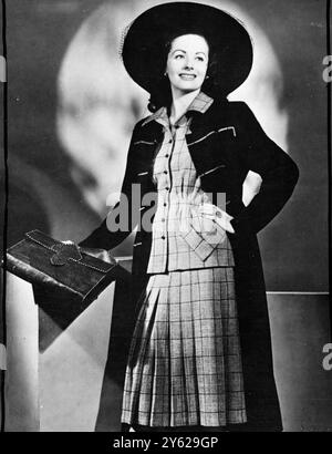 Margaret Lockwood, der junge Star der J. Arthur Rank-Organisation, nimmt sich in diesem vom Wachmann inspirierten Mantel aus marineblauer Wolle mit einer Militärmischung an. Der kurzärmelige Anzug in grauen, marineblauen und roten Tweed hat einen ausgestellten Rock und die Jacke ist an der Taille gerafft und unterstreicht den Hüftbereich. Joy Ricardo hat das atemberaubende Ensemble für die First Lady der britischen Filme geschaffen. 24. Dezember 1947 Stockfoto