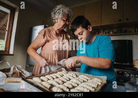 Großmutter und Enkel backen gemeinsam in der Küche Gebäck Stockfoto