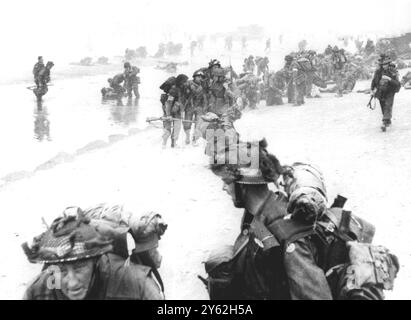 Normandie, Frankreich. D-Day Landungen. Britische Soldaten, viele von ihnen verletzt, landen am Sword Beach. 1944 'der Auslöser klickte um 8:32 Uhr, als Queen Red Beach nahe La Breche, Hermanville-sur-mer unter Granulat und Mörserfeuer geriet. Im Vordergrund und rechts befinden sich Spangen von 84 Royal Engineers der Field Company. Hinter ihnen bereiten sich schwer beladene Sanitäter von 8 Feldambulanten des Royal Army Medical Corps vor, von denen einige verwundete Männer behandeln, um den Strand zu verlassen. Im Hintergrund schwärmen Männer des 1. Bataillons, des Suffolk-Regiments und des No. 4 Army Commando von Landefahrzeugen an Land. Andere in Stockfoto