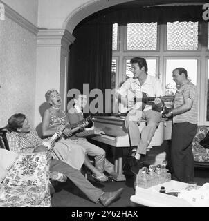 Roger Moore 1958. Im britischen Haus, das er mit seiner Frau Dorothy Squires teilte, The Mount, Wansunt Road, Bexleyheath. Piano-Spieler ist Tony Osborne, weit links Gary Miller (Sänger, großer Hit Robin Hood-Thema) ganz rechts Robert Brown, dann Squire Gurth in Ivanhoe mit Moore, später M in den James-Bond-Filmen von 1981. Stockfoto