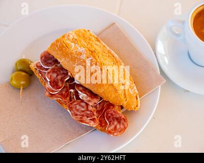 Spanisches Frühstück: Geräuchertes Würstchen-Fuet-Sandwich und Oliven in der Nähe Stockfoto