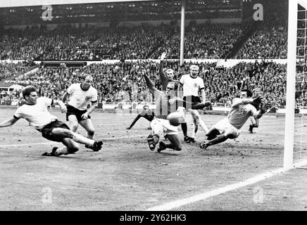 Der World Cup Shocker ist nur wenige Sekunden vor dem WM-Finale und Wolfgang Weber aus der Bundesrepublik Deutschland trifft den Ball am Englands Gordon Banks, Torhüter, vorbei, um heute im Wembley-Stadion den Equalizer zu holen. In der darauf folgenden Verlängerung erzielte England zwei Treffer und erreichte 4-2 Sieger. Ebenfalls auf diesem Bild sind der westdeutsche Kapitän Uwe Seeler, (zweite links) Englands Ramon Wilson (dunkles Hemd); hinter Wilson ist Moore, der englische Kapitän; Schnellinger (weißes Hemd) und im Hintergrund ganz rechts Jackie Charlton, gerade gesehen im Hintergrund, Mitte, George Cohen, der andere englische Fu Stockfoto