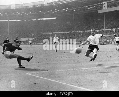 Hurst führt England auf die Siegerpiste, die ihm charakteristisch die Wangen aufbläht, und Geoff Hurst schleudert den Ball an Wili Schulz (Westdeutschland) vorbei, um Englands drittes Tor in der Verlängerung des WM-Finales in Wmbley zu erzielen. Im Zentrum steht Franz Beckenbauer England, der am 4-2 30. Juli 1966 gewann Stockfoto