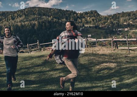 Keine Sorge. Verspieltes junges Paar lächelt beim Laufen im Tal in den Bergen im Freien Stockfoto