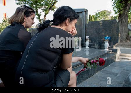 Mutter und Tochter in Trauer, in schwarzer Kleidung, mit einer Blume und Trauer um einen verstorbenen geliebten Menschen auf dem Friedhof Stockfoto