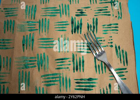 Nahaufnahme von dekorativen Stempeln mit Gabel in der Farbe und Papierbögen. Erstellen Sie einzigartiges Geschenkpapier, DIY-Bastelprojekt für personalisierte Designs. Stockfoto