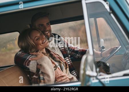 Einfache Freude an Liebe. Wunderschönes junges Paar, das in einem Minibus im Retro-Stil sitzt und lächelt Stockfoto