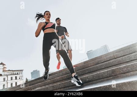 Auf der Treppe trainieren. Niedriger Blickwinkel auf ein junges Paar in Sportkleidung, das zusammen die Treppe hinunterläuft Stockfoto