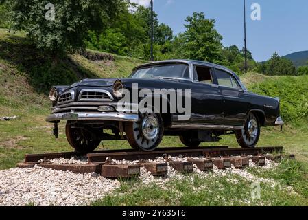 Mokra Gora, Serbien - 22. Juni. 2023: Retro-Auto Chrysler New Yorker Deluxe mit Laufrädern, die für das Fahren auf Bahnschienen vor Schmalspurwagen modifiziert wurden Stockfoto