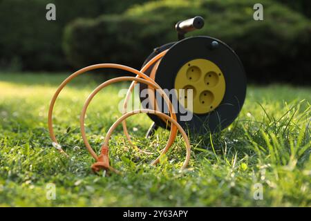 Eine Verlängerungskabelrolle auf grünem Gras im Freien Stockfoto