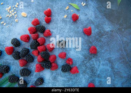 Brombeeren und Himbeeren auf blauem Stein Hintergrund mit Kornflocken herum, isoliert Stockfoto