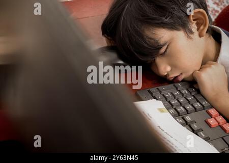 Asiatischer Junge schlief während der Online-Schule von zu Hause aus vor seinem Computer ein Stockfoto