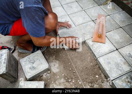 Ein Mann, der zu Hause Betonblockarbeiten für die Terrasse im Garten macht Stockfoto