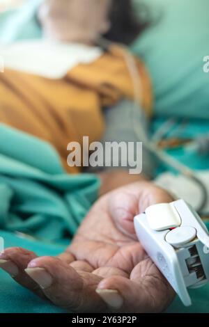 Stationäre kranke asiatische ältere Frau in Behandlung als stationäre liegend im Bett Oximeter am Daumen zur Messung von Sättigung, Puls und Herzfrequenz Stockfoto