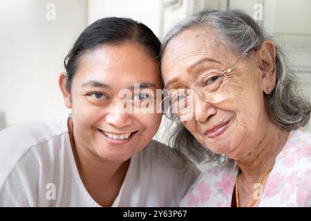 Gesunde und glückliche asiatische Seniorin zusammen mit reifer erwachsener Tochter posiert vor der Kamera Stockfoto
