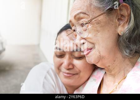 Eine asiatische alte Mutter lächelt und glücklich, von ihrer Tochter umarmt zu werden Stockfoto