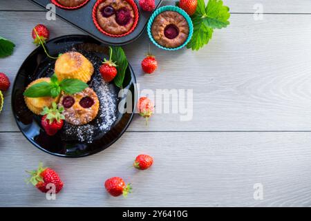 Süße Quark-Muffins mit Erdbeerfüllung, auf einem Teller auf einem Holztisch. Stockfoto
