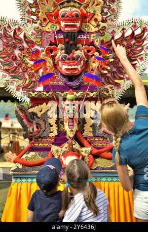 Frauen und Kinder Touristen, die auf eine traditionelle, skulpturale Kunst aus Reismehl (Opfergabe für spirituelle Zeremonie) in Bali, Indonesien, achten. Stockfoto