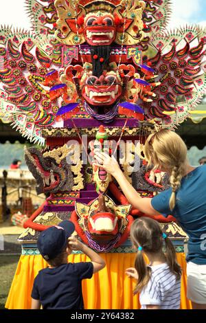 Frauen und Kinder Touristen, die auf eine traditionelle, skulpturale Kunst aus Reismehl (Opfergabe für spirituelle Zeremonie) in Bali, Indonesien, achten. Stockfoto