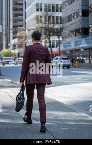 Geschäftsmann mit Aktenkoffer und geht zur Arbeit. Mann im klassischen Anzug mit Aktentasche, der draußen läuft. Junger Mann mit Aktentasche in Eile, schnell zu gehen Stockfoto