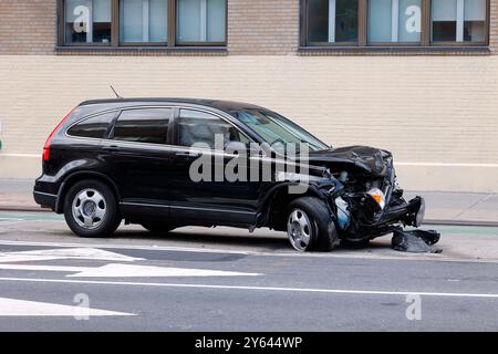 Ein zerstörtes Auto, das an einem Verkehrsunfall beteiligt war, sitzt am Straßenrand verlassen. Die Vorderseite des Autos, die Knautschzone, absorbierte den größten Teil des impac Stockfoto