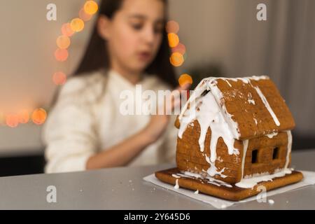 Ein Mädchen spielt mit einem Lebkuchenhaus für traditionelle Weihnachtsdekoration Stockfoto