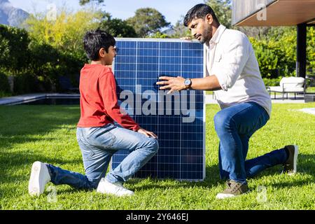 Installation von Sonnenkollektoren im Hinterhof, indischer Vater und Sohn lernen mehr über erneuerbare Energien Stockfoto