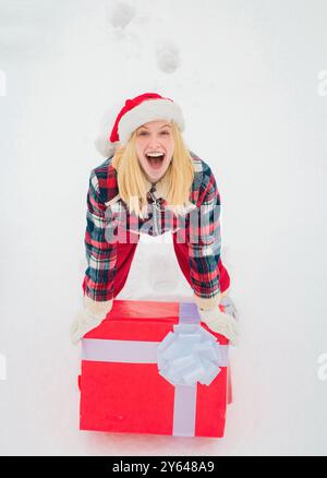 Weihnachtsfrau mit einem riesigen Geschenkkarton. Frau präsentieren rote Geschenkbox mit Schleife isoliert auf weißem Hintergrund. Große Geschenkbox. Hipster Mädchen mit Stockfoto