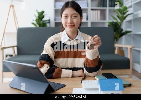 Frau hält den Schlüssel zu ihrem neuen Haus und sichert sich einen Kredit, um die finanziellen Aspekte ihres Eigenheims zu verwalten, und die Finanzierung und Verantwortung miteinander in Einklang zu bringen Stockfoto