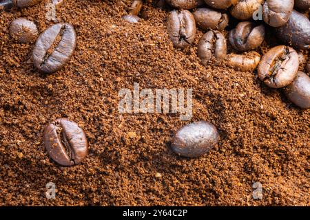 Nahaufnahme der verstreuten Kaffeebohnen auf gemahlenem Kaffee. Stockfoto