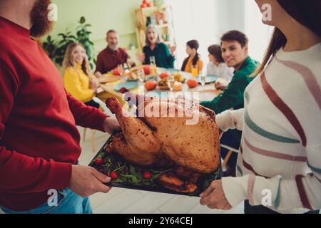 Foto von Ehepartnern, die an einem Feiertag gefüllte, leckere traditionelle fleischputen servieren, Thanksgiving-Tag drinnen Stockfoto