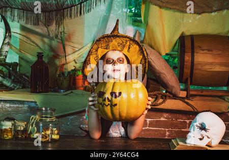 Lustige Halloween-Kinder. Fröhliche Kinder an Halloween. Halloween-Feiertagskonzept. Junge, der Spaß mit Halloween-Kürbis hat. Stockfoto